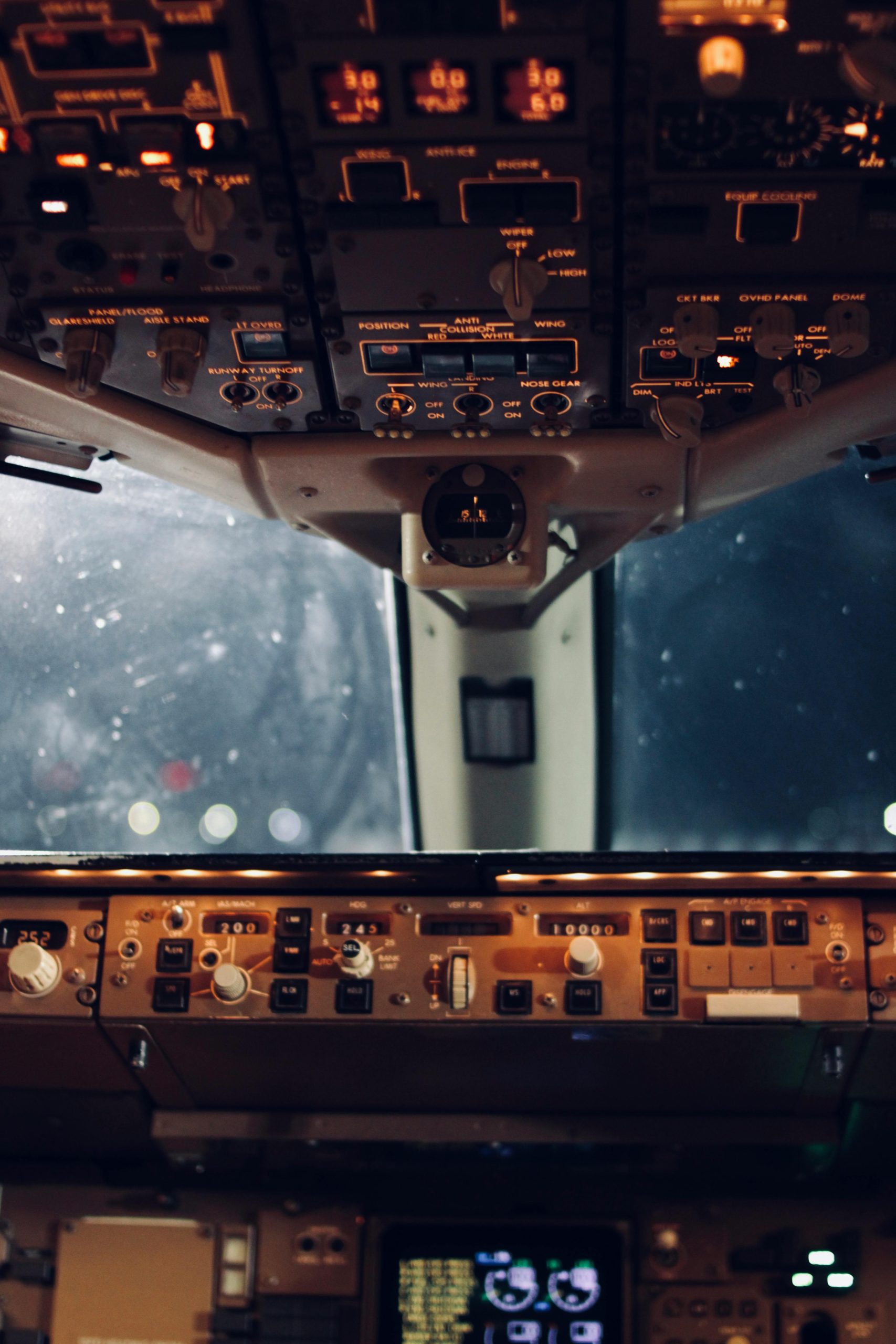 Close-up view of an aircraft cockpit's illuminated controls and instruments at night.